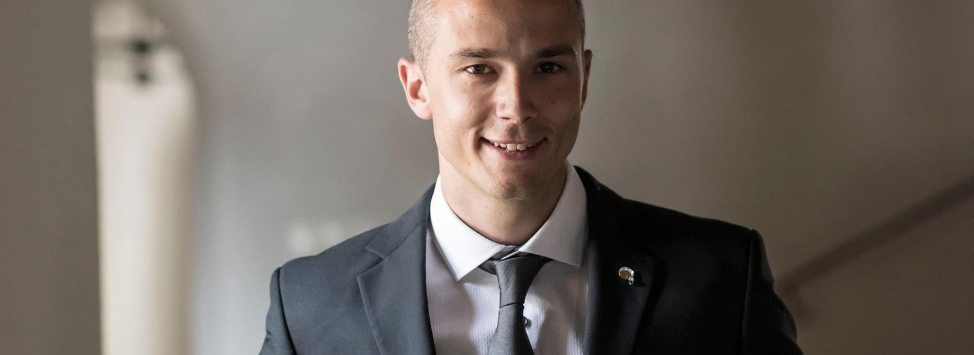 Portrait of Bastian Winkler, who is shown smiling in an elegant suit.