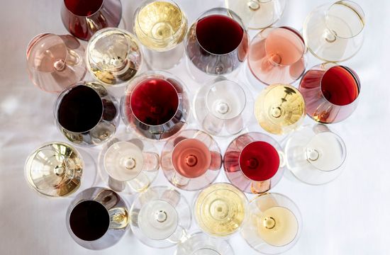 Many wine glasses arranged side by side, photographed from above. You can spot various wines: white, red, sparkling, and rosé, each served in a different glass.