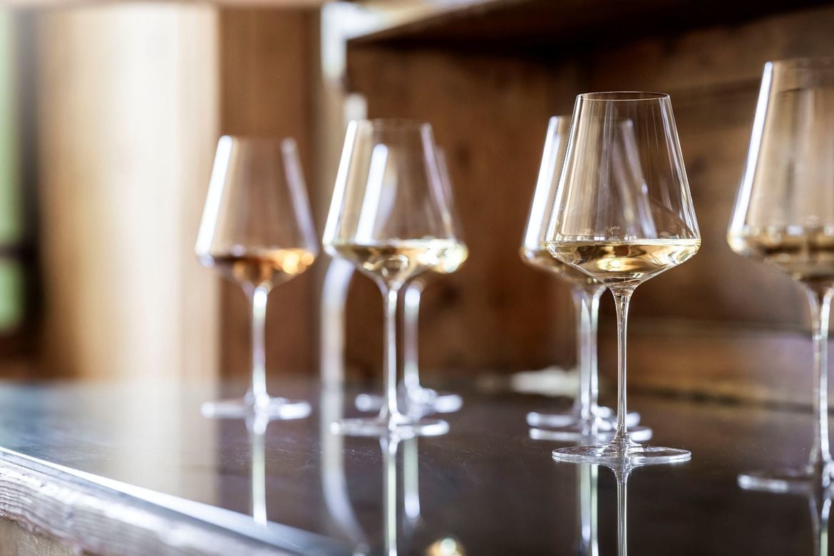 A series of medium-sized wine glasses filled with white wine.