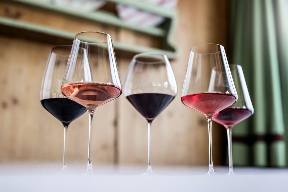 A series of large red wine glasses with wide openings, including two with narrower rims.