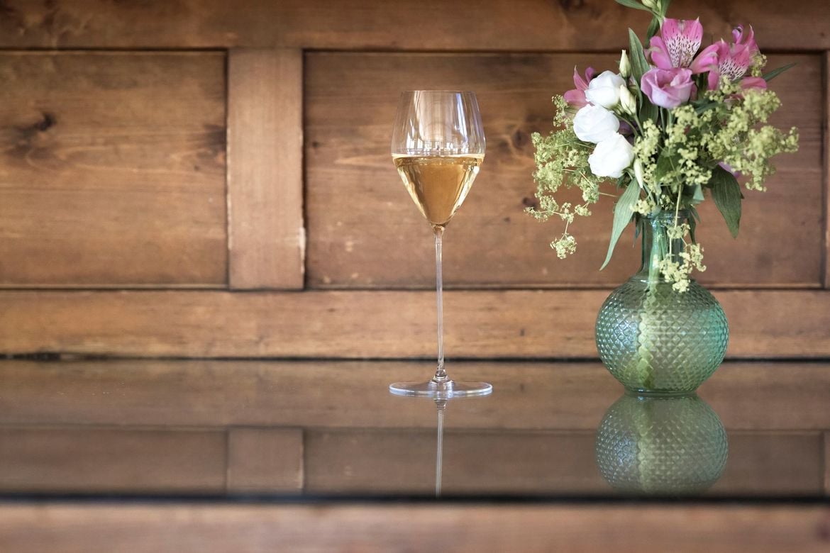 A filled flute next to a bouquet of flowers.