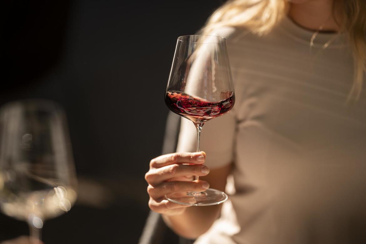 A woman swirling a glass of red wine.