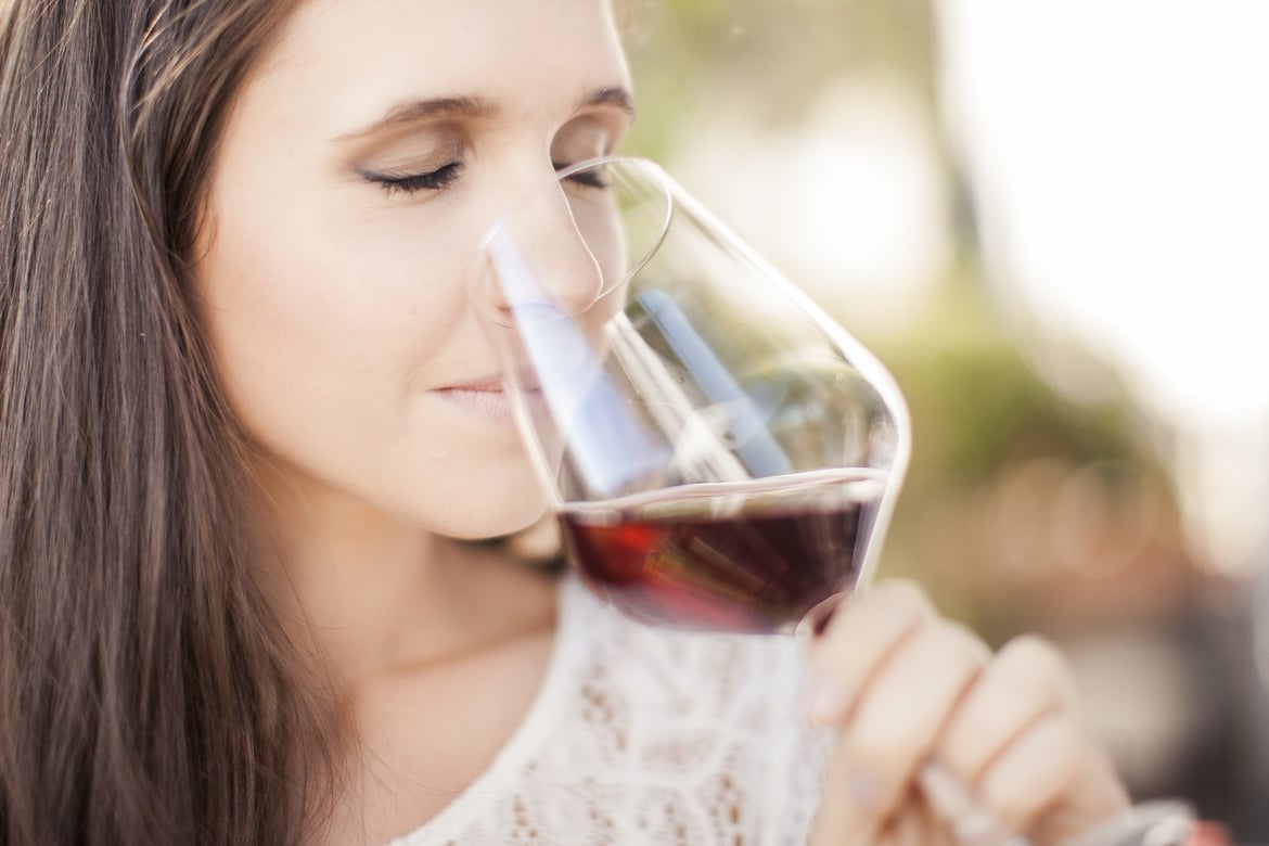 A woman smelling a glass of red wine.